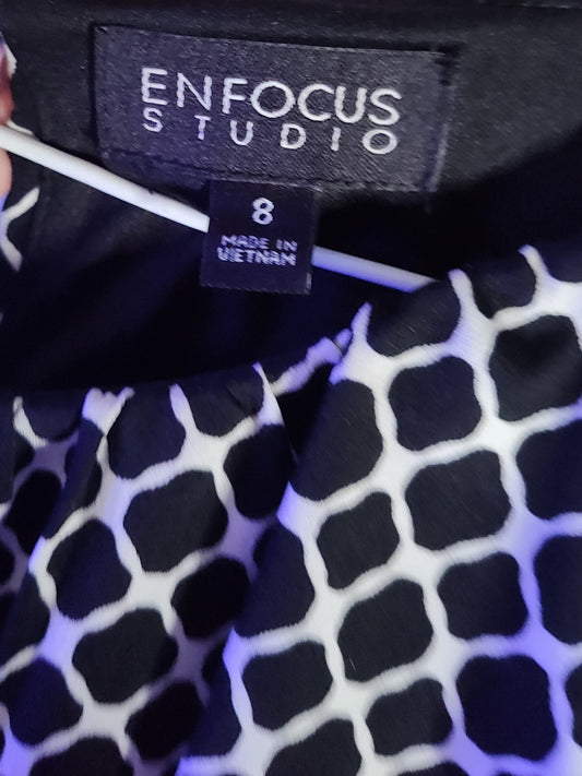 Close-up of a garment with 'Enfocus Studio' label and black and white pattern.
