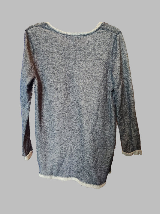 Person holding a gray sleeveless top with white trim in an indoor setting