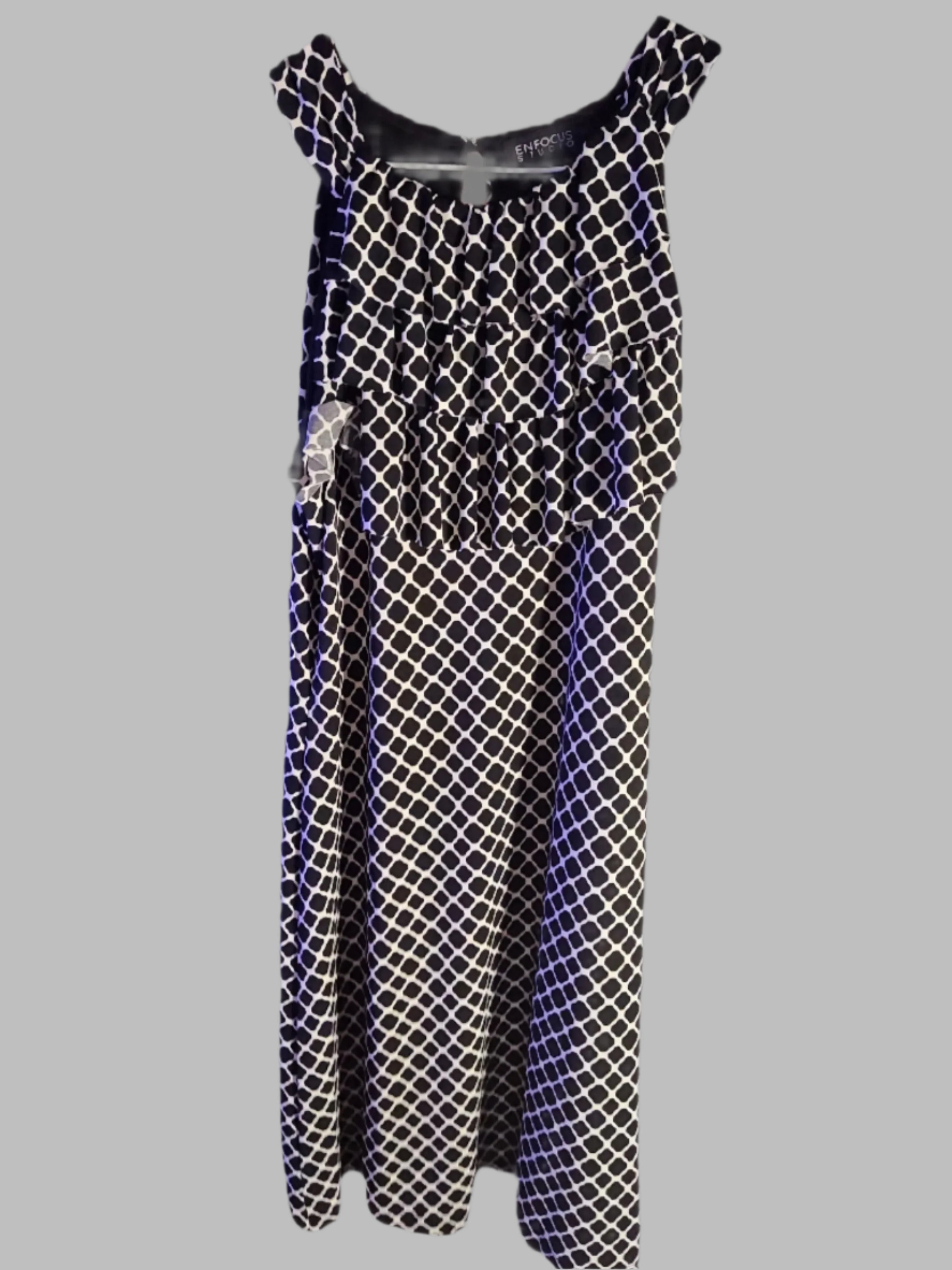 Black and white patterned dress on a hanger against a gray background