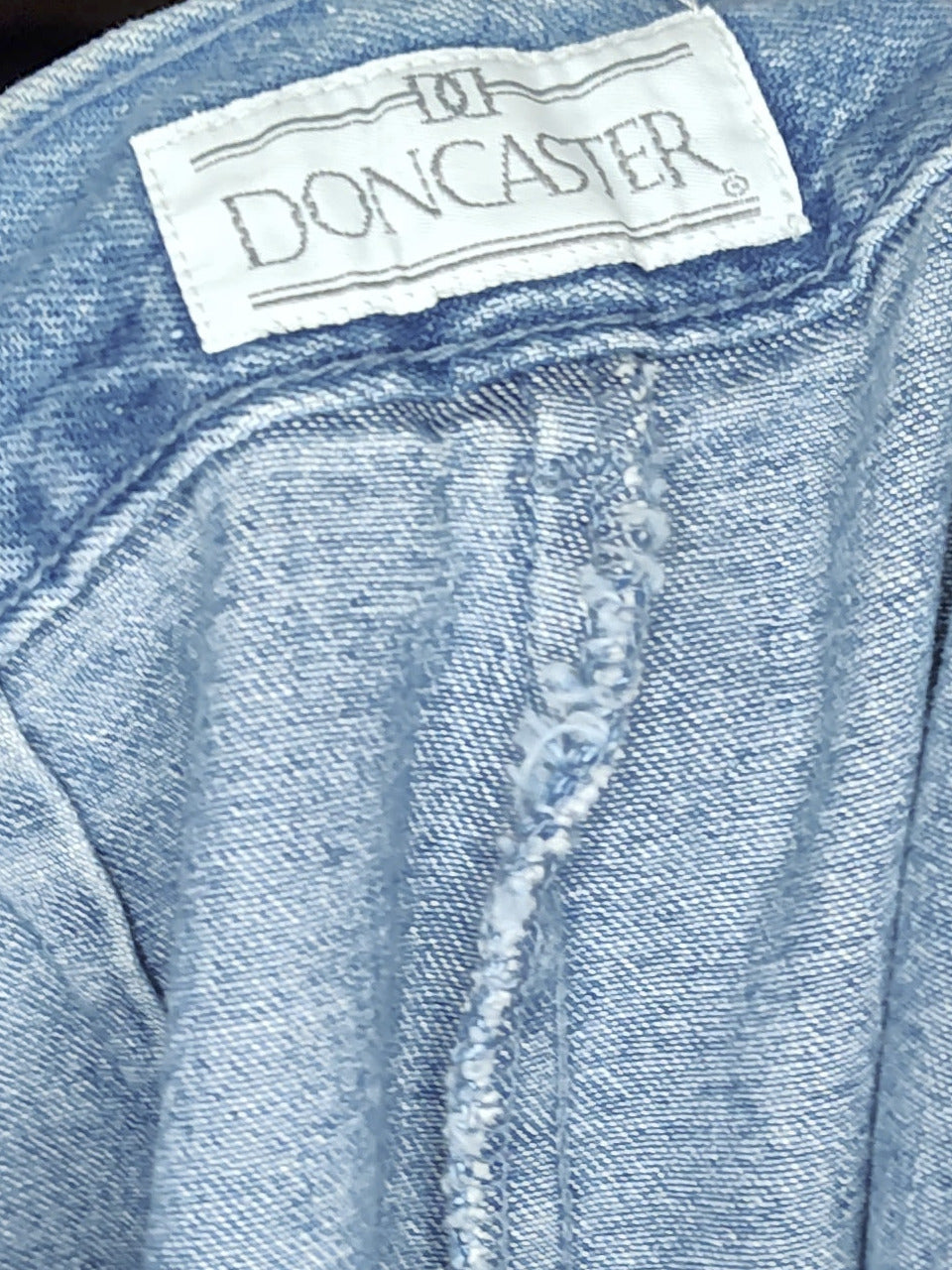 Close-up of a blue denim jacket with a brand label on a blurred background