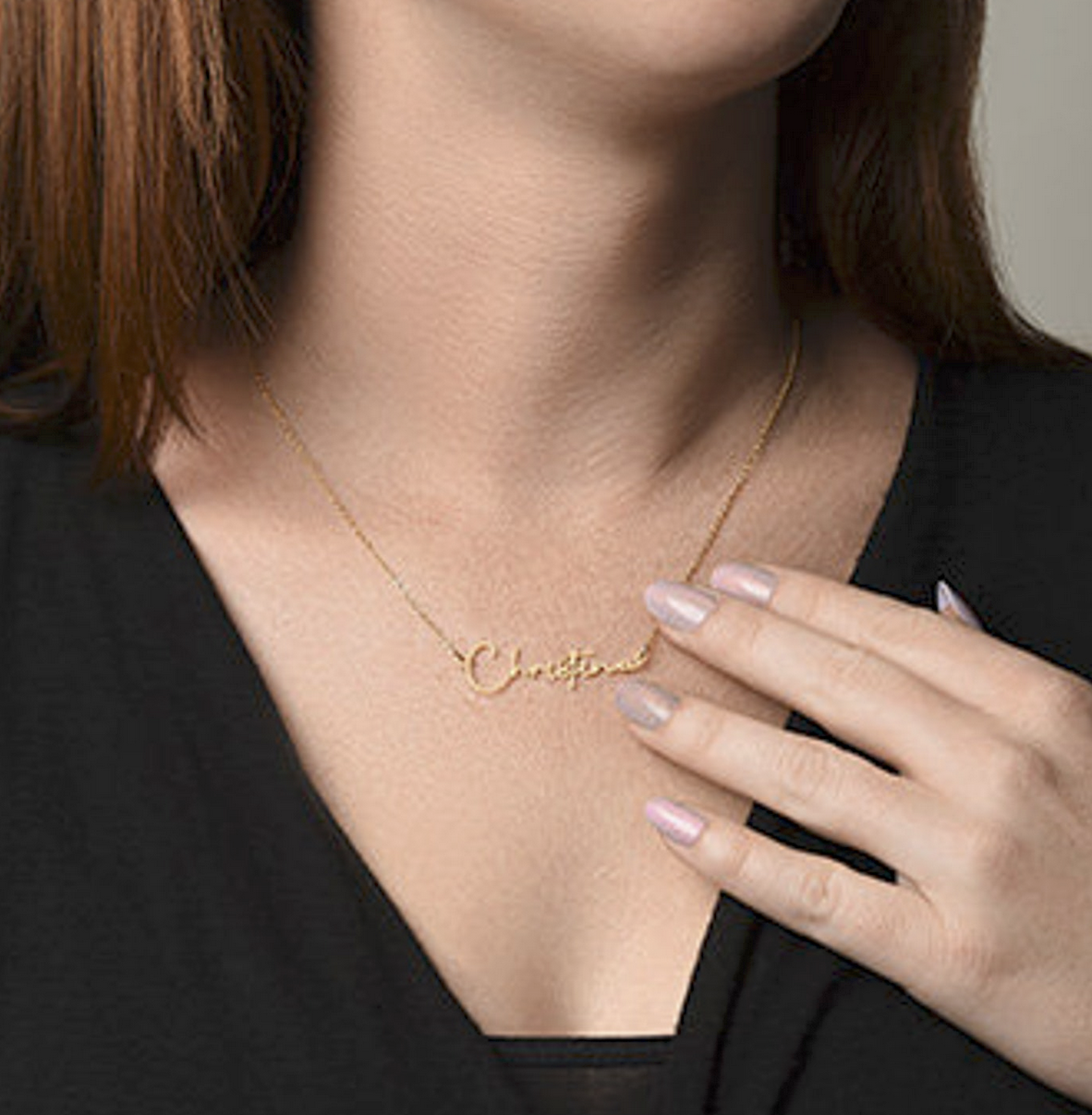 Gold necklace with 'Christina' on a person wearing a black top.