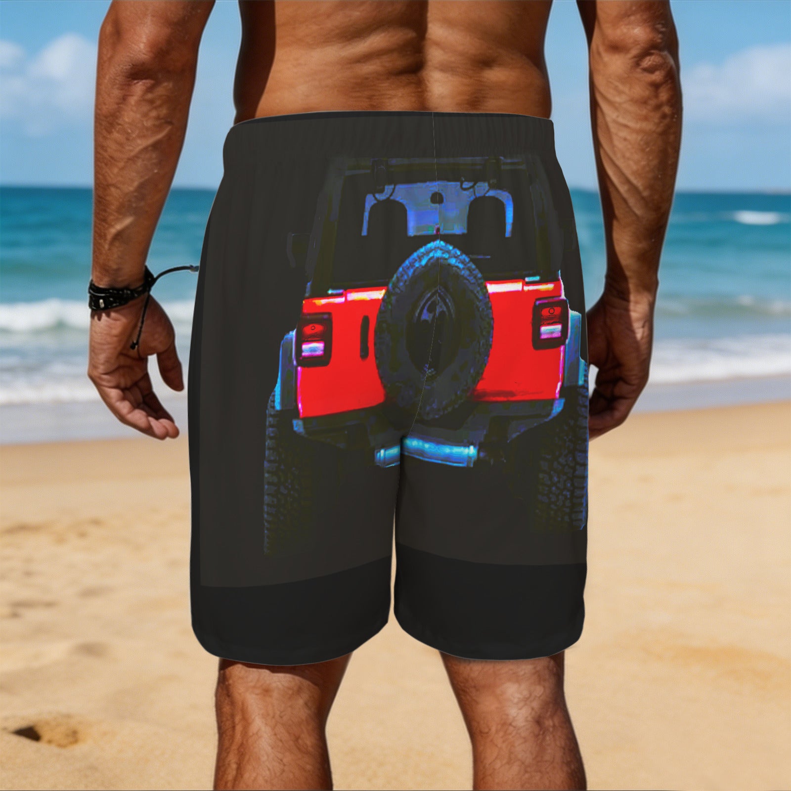 Person wearing black shorts with a graphic design of a red truck on a beach.