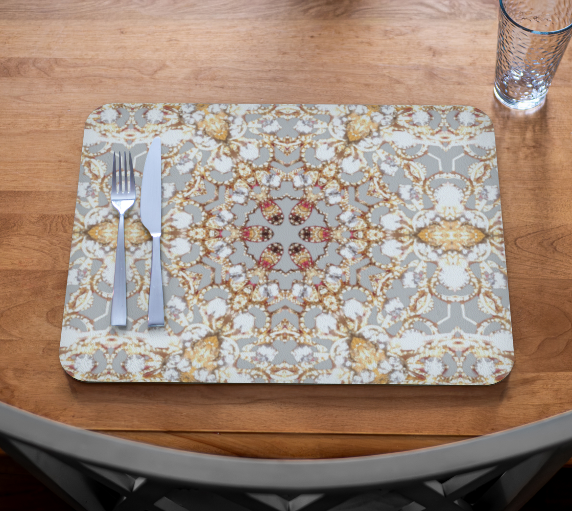 Decorative placemat with floral pattern on a wooden table with cutlery and glass.