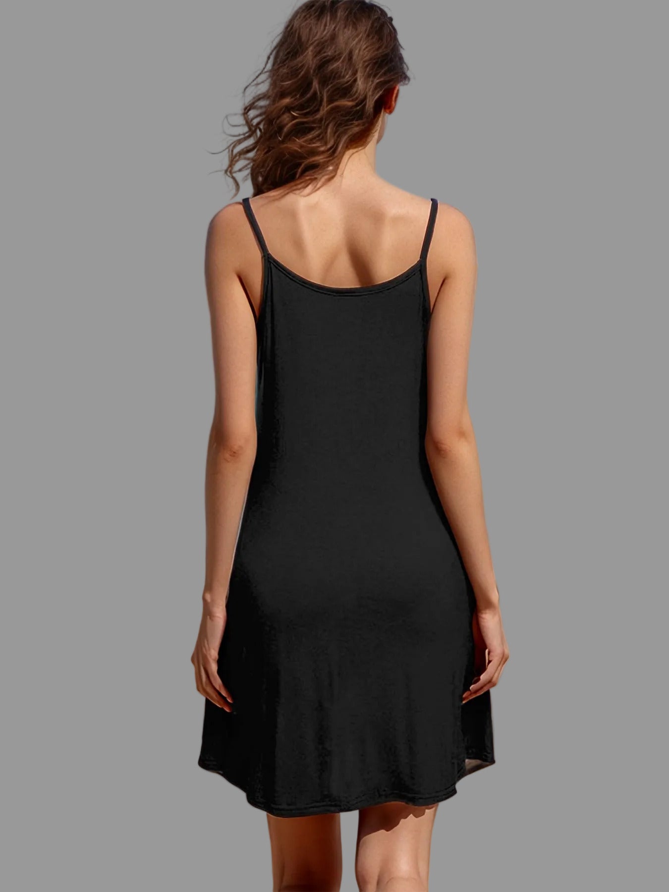 Woman in a black dress standing on a beach with ocean view