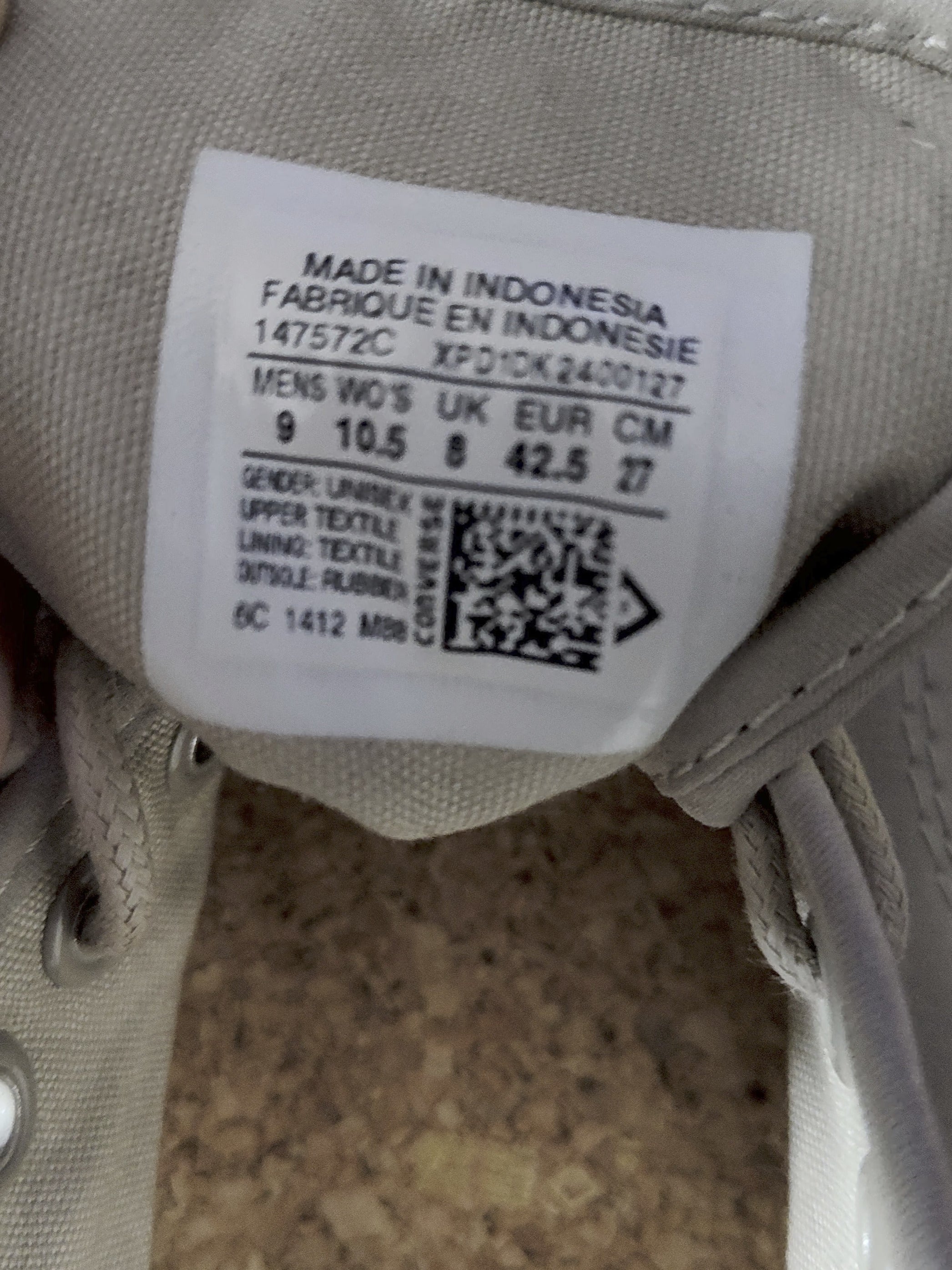 Close-up of a shoe label with text and a QR code on a beige shoe.