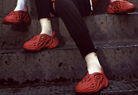 Two people sitting on a set of stairs wearing red shoes with visible branding.